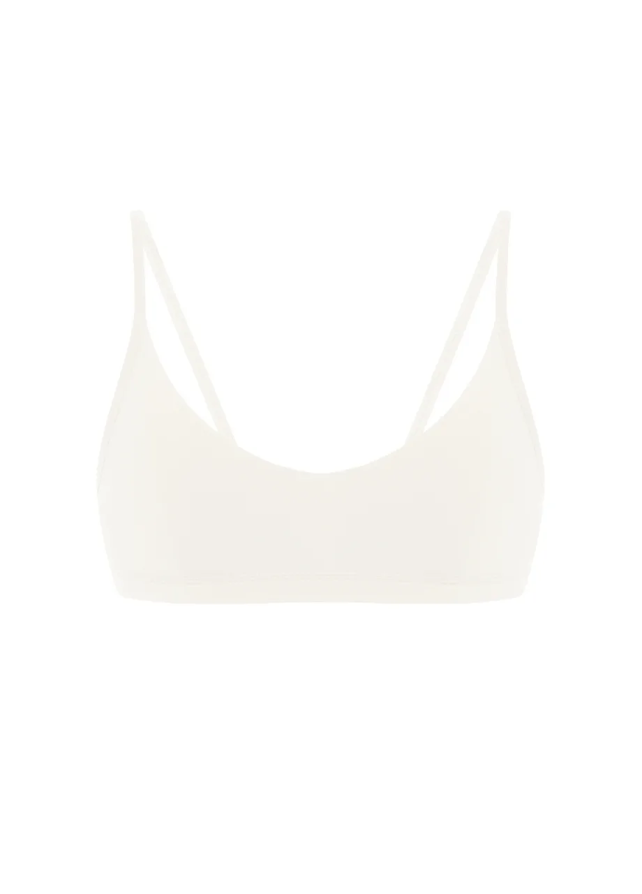 11 › Str/Cd Wear White bralette with thin straps and scoop neckline, seamless design on a white background.