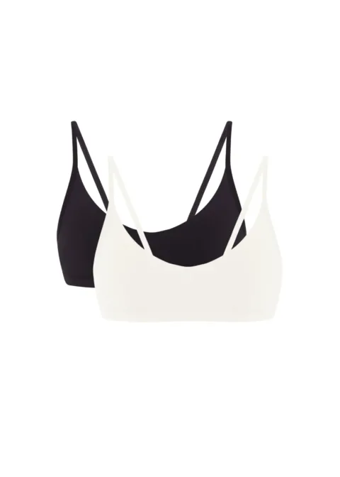 Two bralettes, one white and one black, layered with thin straps visible against a white background.