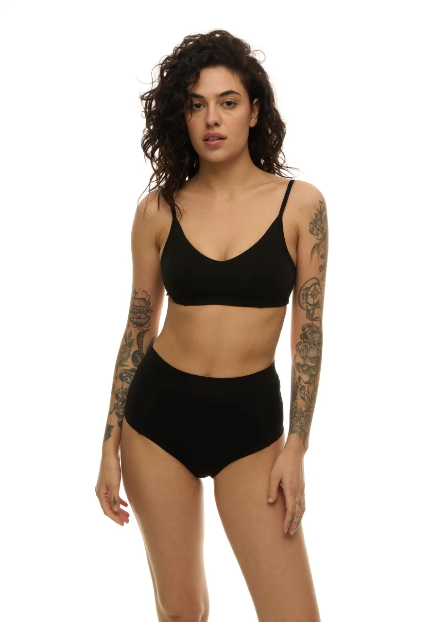 WP61128 › Str/Cd Wear Woman in a black bralette and high-waisted briefs, standing with arms at her sides.