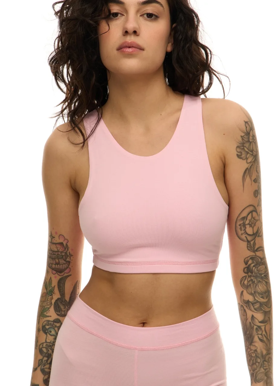 WS509512 › Str/Cd Wear Woman modeling a light pink sports bra and matching high-waisted leggings; tattoos on both arms visible.