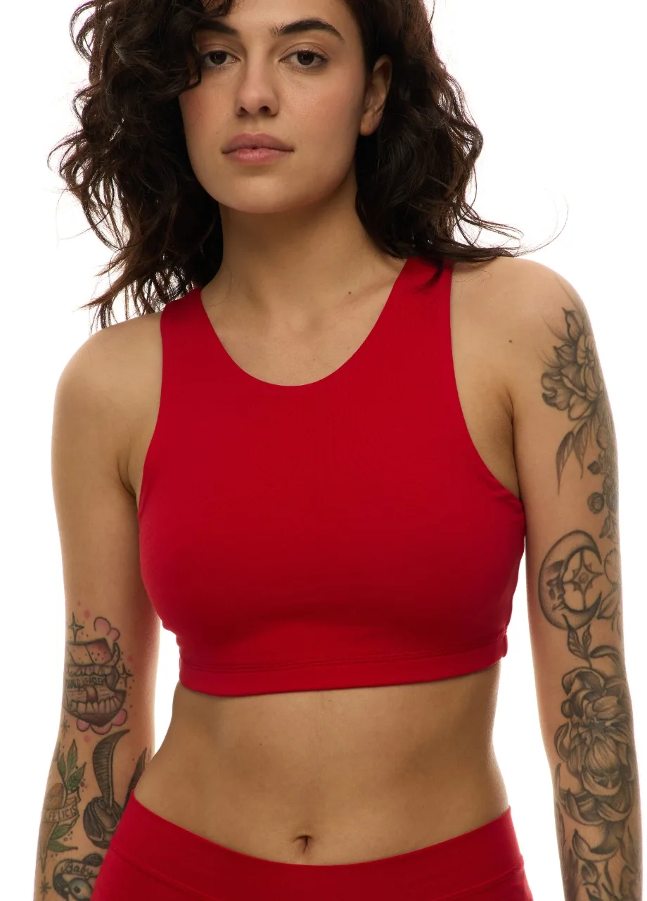WS509514 › Str/Cd Wear Woman in a red athletic crop top with tattoos on both arms and a neutral expression against a white background.