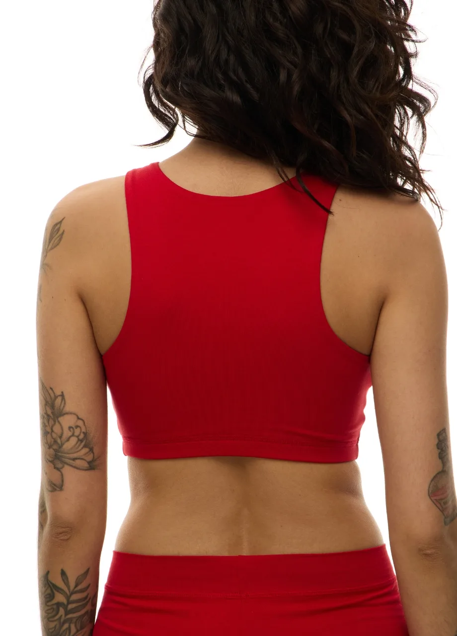 WS509516 › Str/Cd Wear Back view of a person with dark wavy hair wearing a red sports bra and matching red bottoms, showing tattoos on both arms.