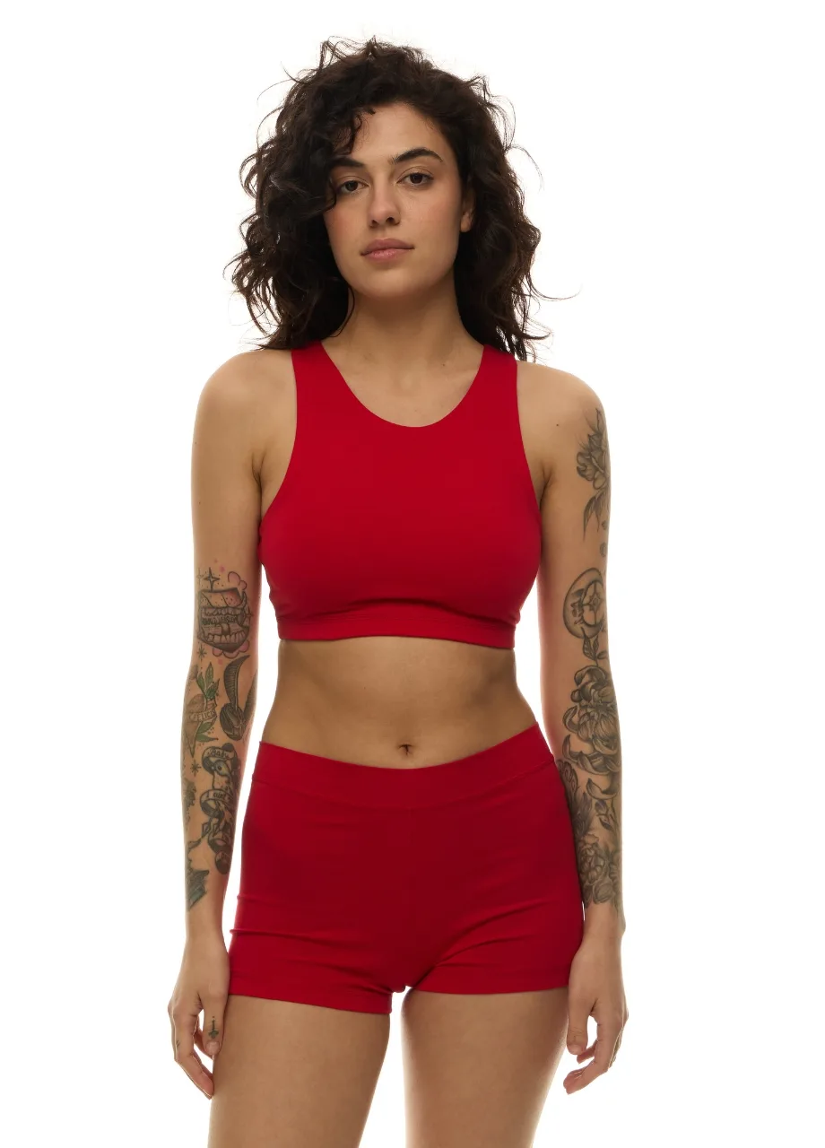 WS509517 › Str/Cd Wear Woman wearing a red sports bra and matching shorts, standing and facing the camera with arms at sides.