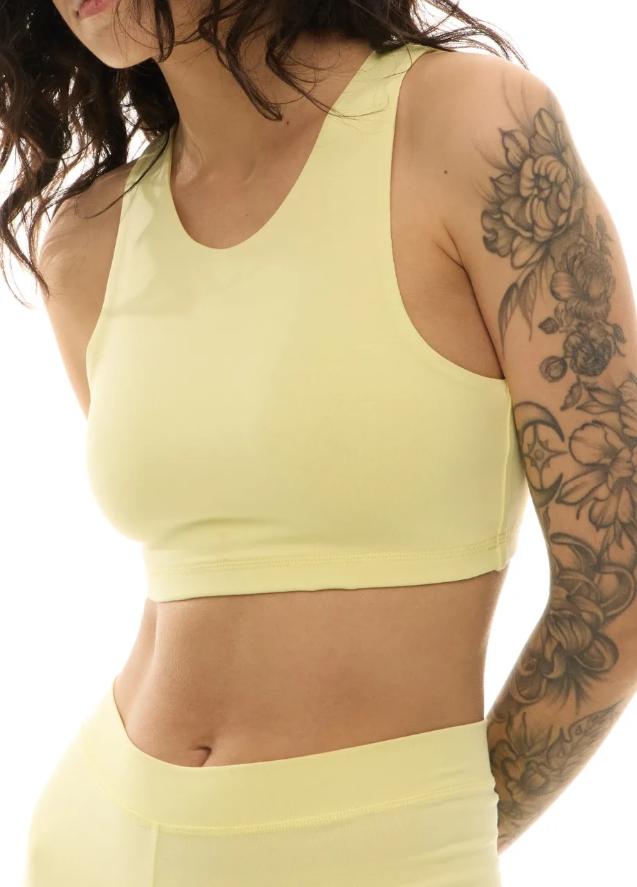 WS509521 › Str/Cd Wear Woman wearing a pale yellow sports bra and matching high-waisted leggings, with floral tattoos along her right arm visible.