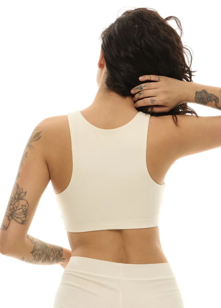WS50954 › Str/Cd Wear Back view of a tattooed person in a white sports bra and bottoms, hand resting on the back of their neck.