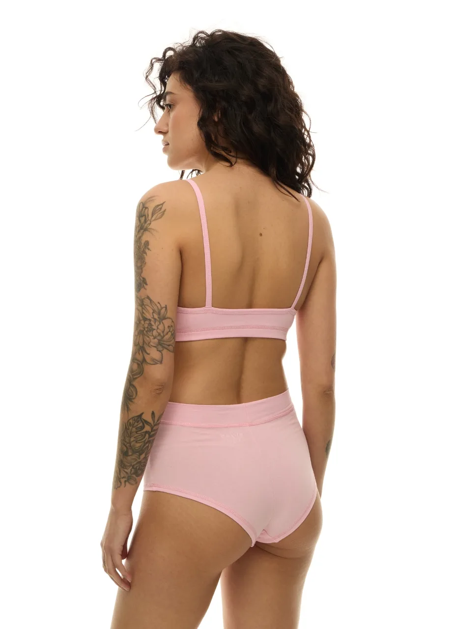 WS511112 › Str/Cd Wear Woman seen from the back wearing light pink bra and high-waisted underwear; floral tattoo on her left arm is visible.