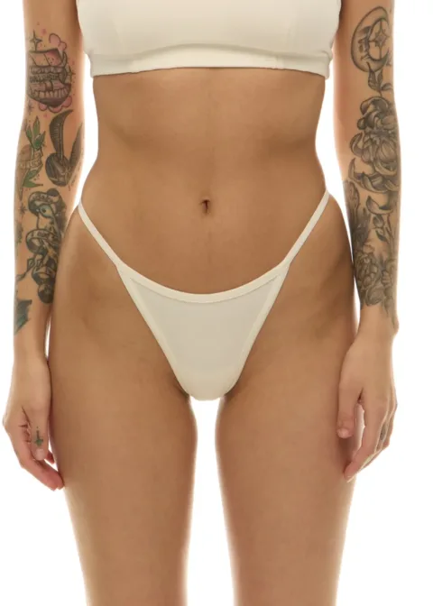 Model wearing a white bikini set (strapless top and high-cut bottoms) with tattoos visible on both arms.