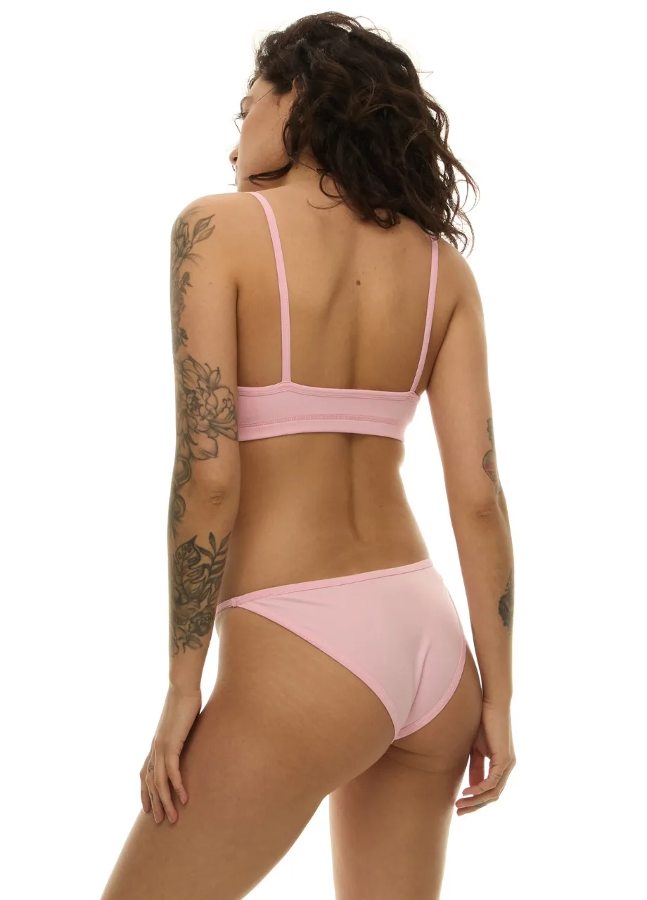 WU1314214 › Str/Cd Wear Woman wearing a pale pink bikini from the back, showing shoulder straps and tattoos on her left arm against a white studio background.