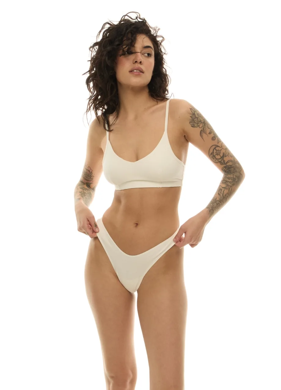 WU131435 › Str/Cd Wear Woman in white underwear posing with hands at her hips; tattoos visible on both arms.