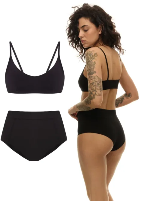 Black bra and high-waisted panties set displayed on a model with shoulder-length hair and tattooed arm, back view visible.