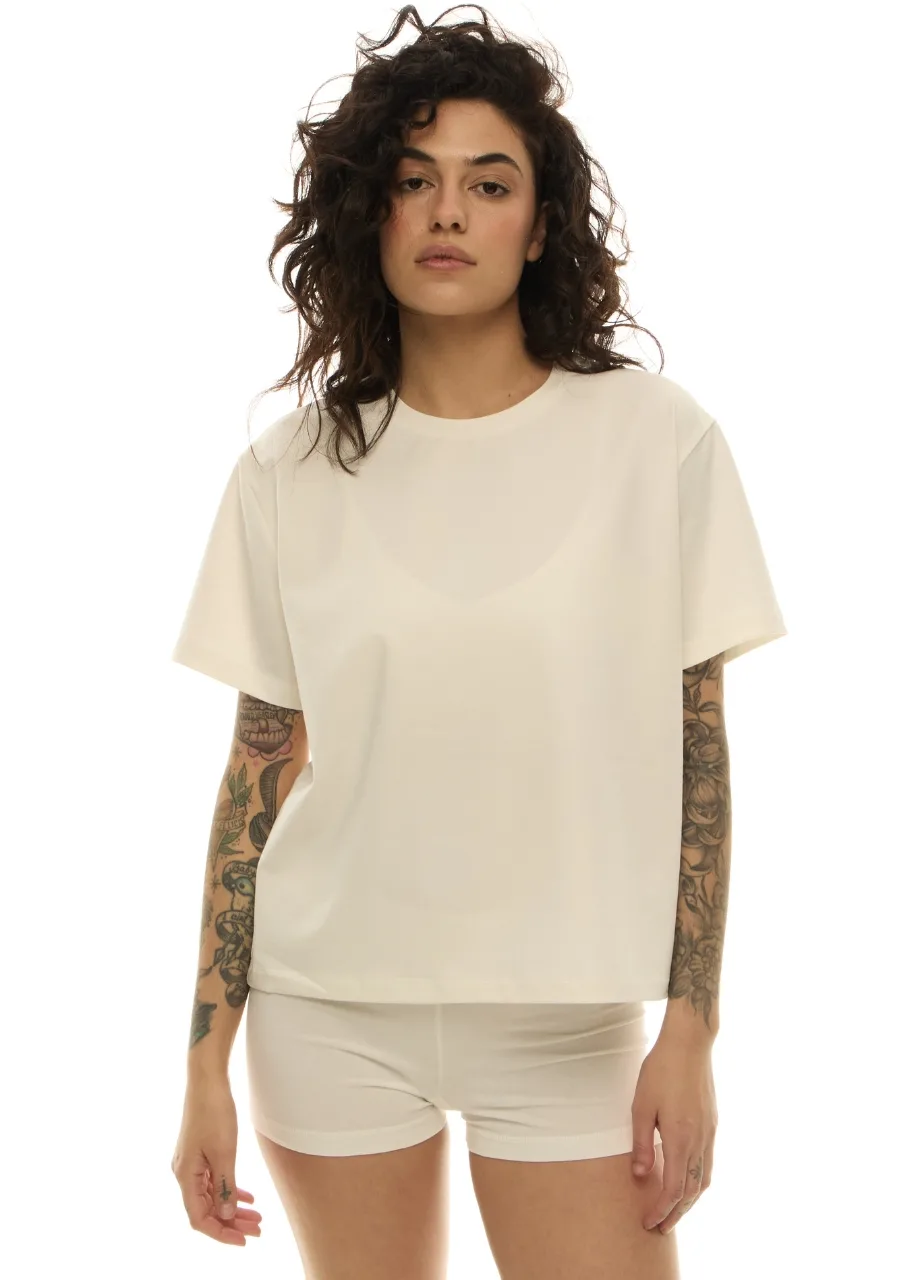 38 › Str/Cd Wear Model with wavy dark hair wearing an oversized cream T-shirt and matching shorts, arms covered in tattoos, against a white background.