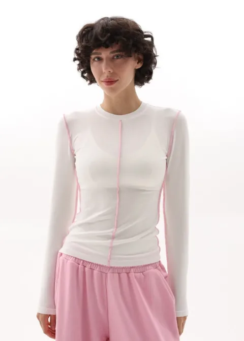 Model wearing a white long-sleeve top with pink seam detailing and light pink shorts with an elastic waistband.