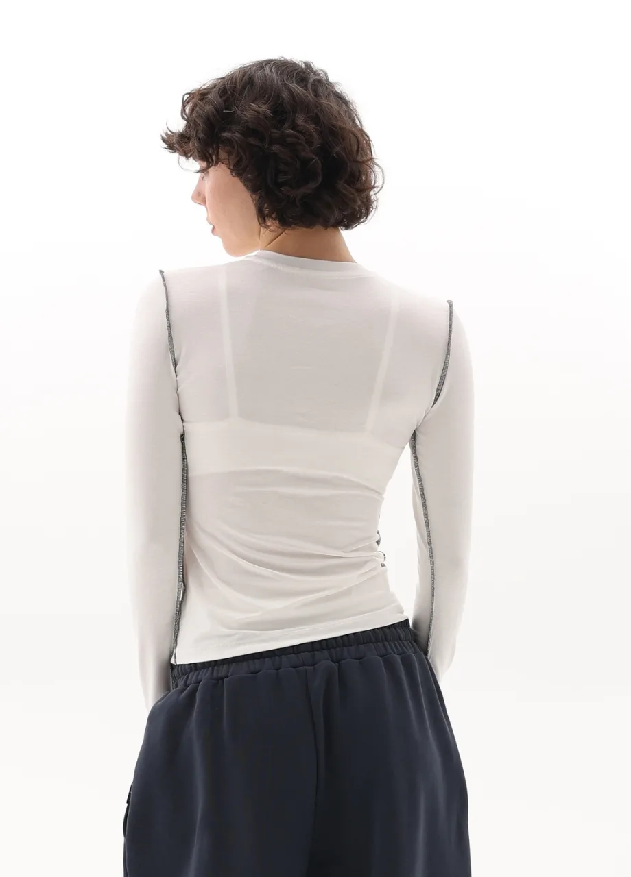 10 › Str/Cd Wear Back view of a person wearing a white long-sleeve top with seam details and navy shorts from behind.